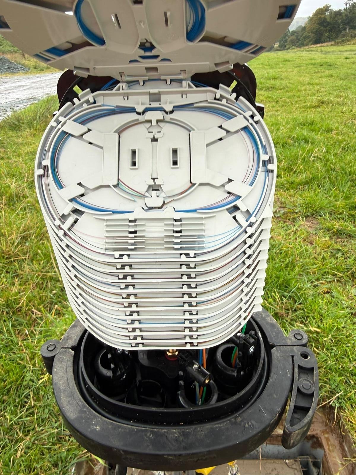 Open fibre closure showing splice trays in a roadside chamber