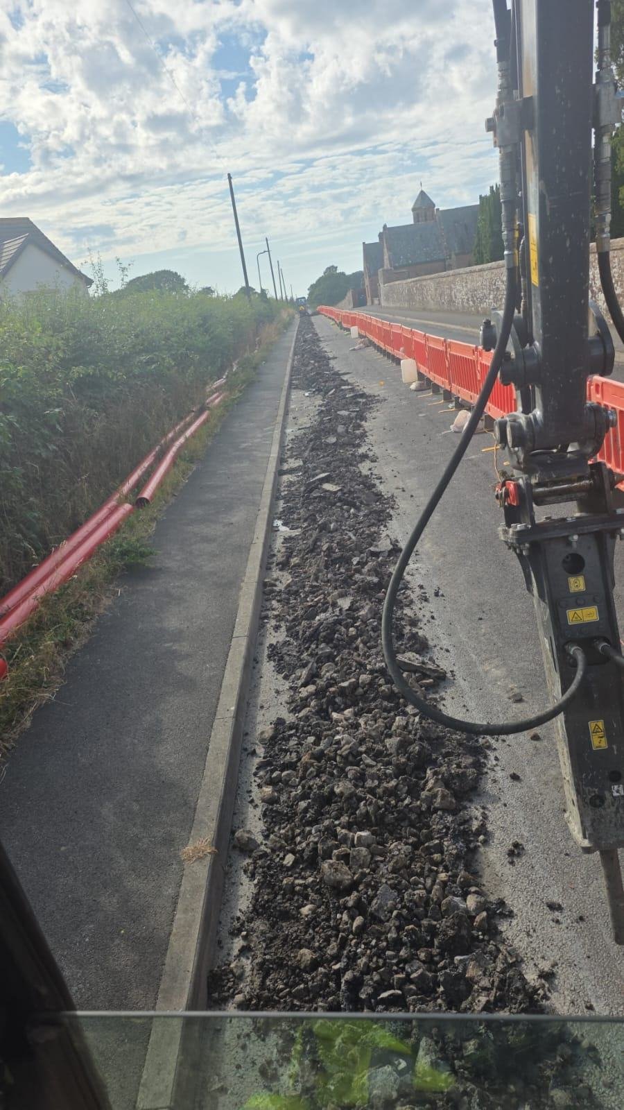 Footway broken out ahead of the duct run, seen from the excavator cab
