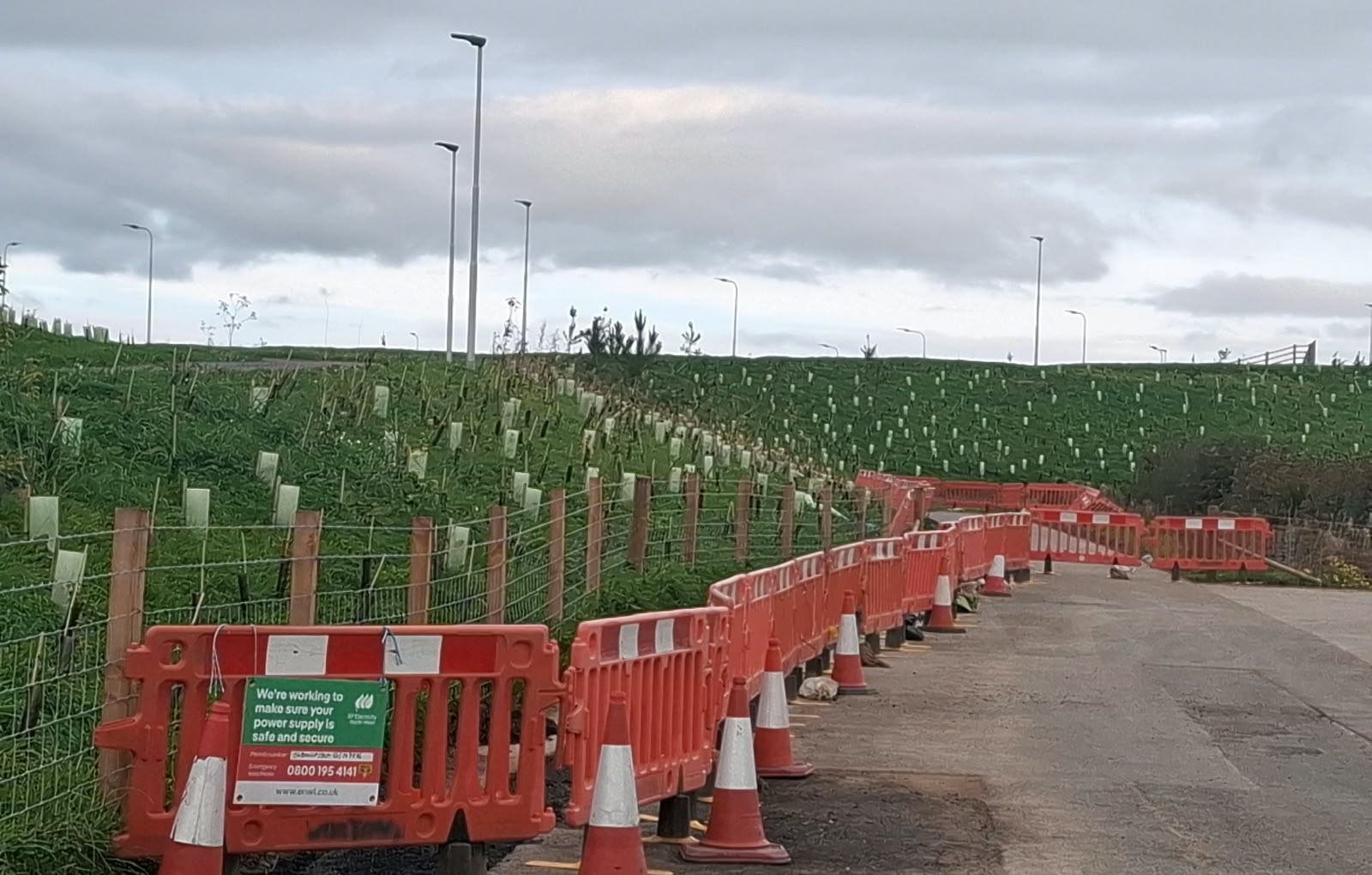 Footway reinstated in fresh tarmac behind barriers and cones